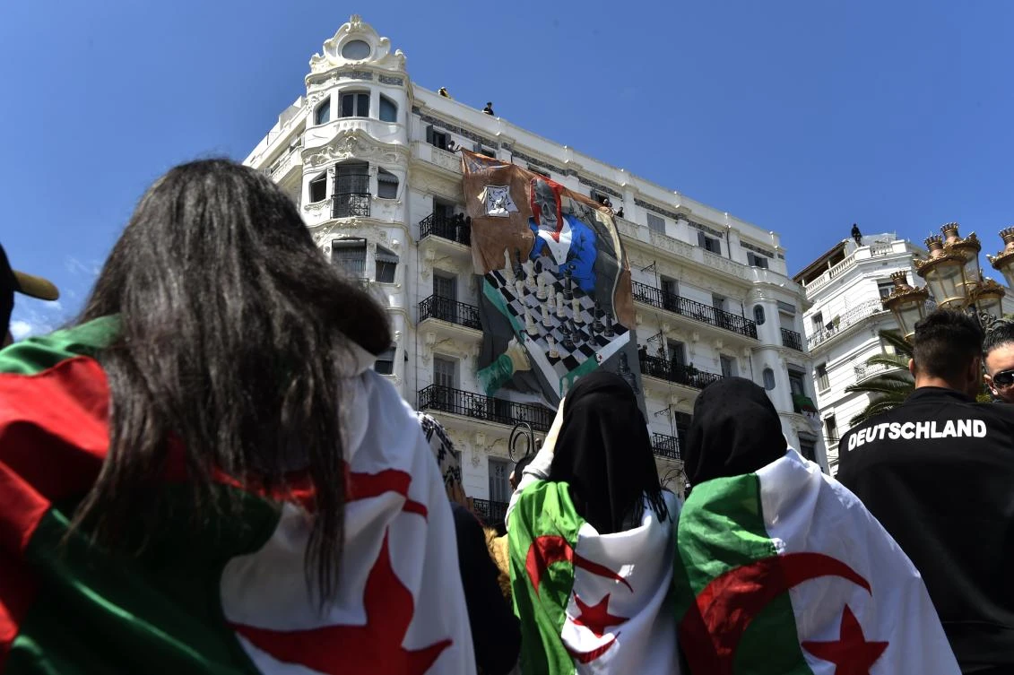 Algerian students watch a banner being fixed on a building's facade on April 30, 2019 as they continue their weekly protests in the capital Algiers. (AFP)