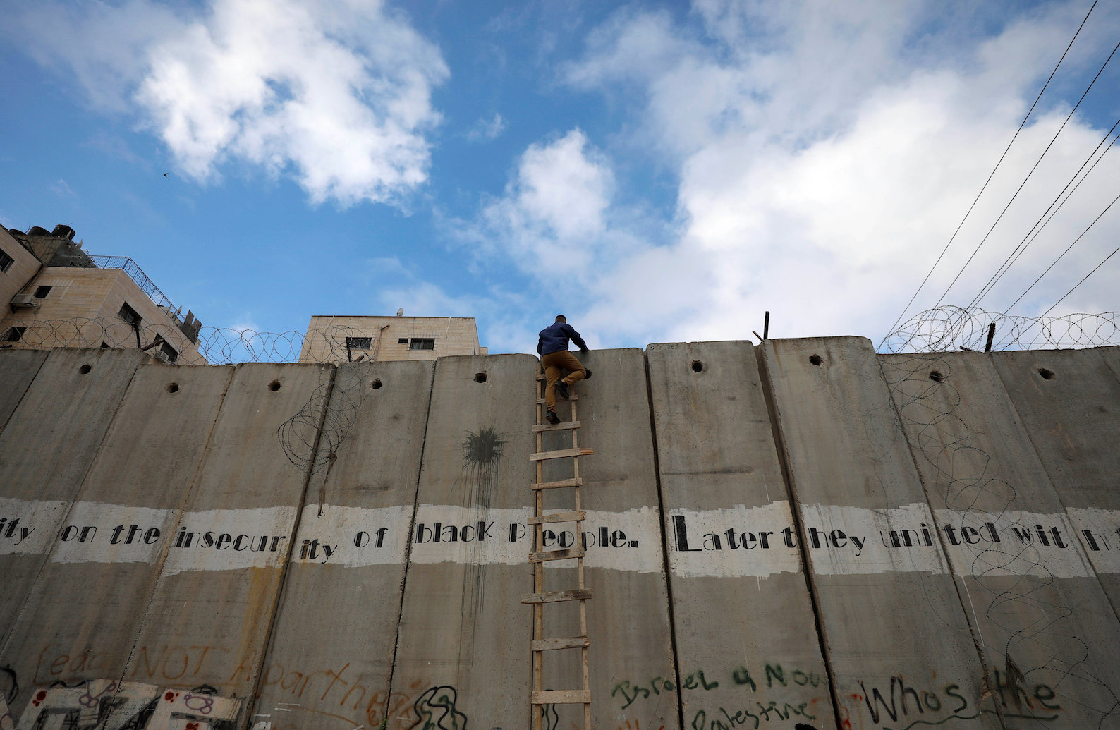A Palestinian uses a ladder to climb over a section of the controversial Israeli barrier as he tries to make his way to attend the first Friday prayers of Ramadan in Jerusalem's Al-Aqsa mosque, near Ramallah in the Israeli-occupied West Bank May 10, 2019. (Reuters)