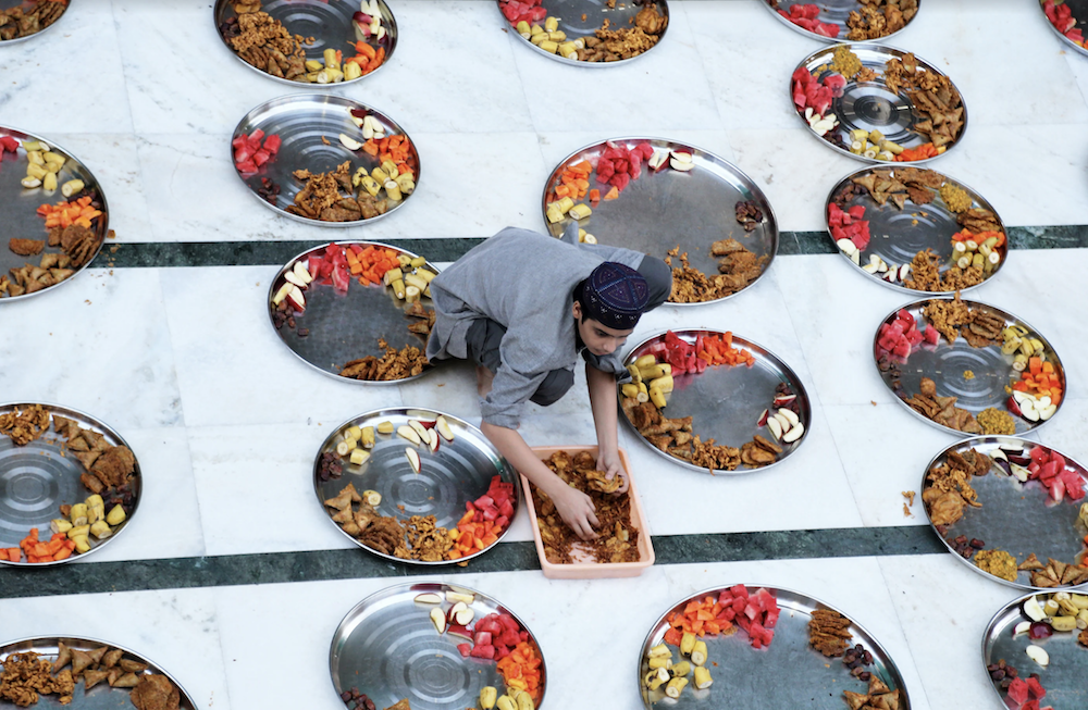 A Muslim boy prepares plates of food for Iftar (breaking fast) meals inside a mosque during the holy fasting month of Ramadan in Mumbai, India, May 10, 2019. (Reuters)
