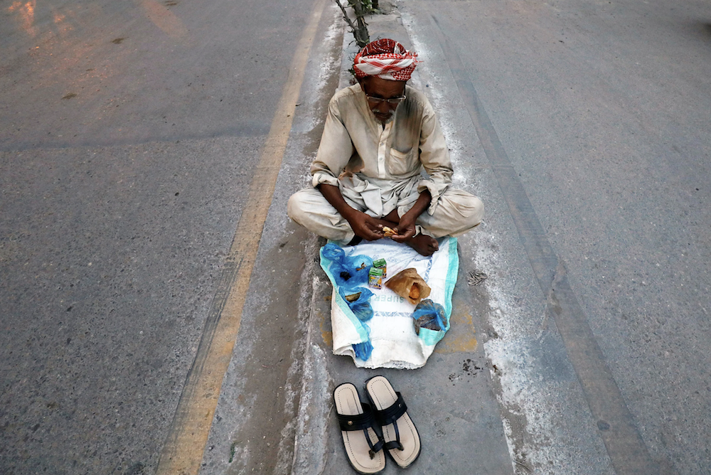An elderly man sits on a road as he breaks fast during the holy month of Ramadan, in Karachi, Pakistan, May 10, 2019. (Reuters)
