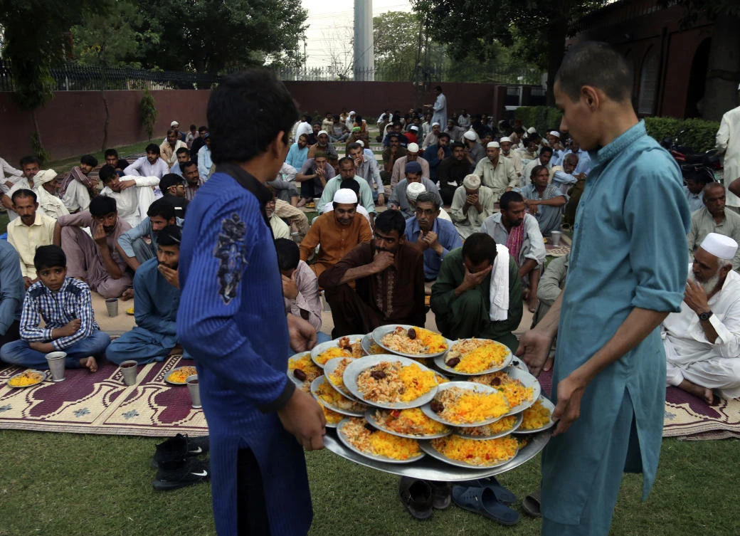 Volunteers distribute food for the "Iftar" meal for Muslims to break their fast at sundown, during the fasting month of Ramadan at a mosque in Lahore, Pakistan, Tuesday, May 7, 2019. Muslims around the world are observing Ramadan, the holiest month in Islamic calendar. (AP Photo/K.M. Chaudary)
