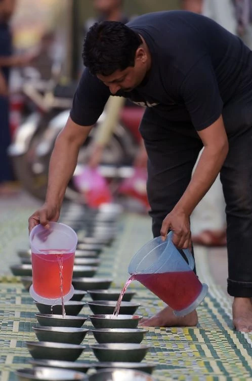 A Pakistani volunteer fills pots with drinks for Muslim devotees prior to breaking their fast on the first day of the holy month of Ramadan along the roadside in Rawalpindi on May 7, 2019. Muslims throughout the world are marking the month of Ramadan, the holiest month in the Islamic calendar during which Muslims fast from dawn until dusk. / AFP / AAMIR QURESHI