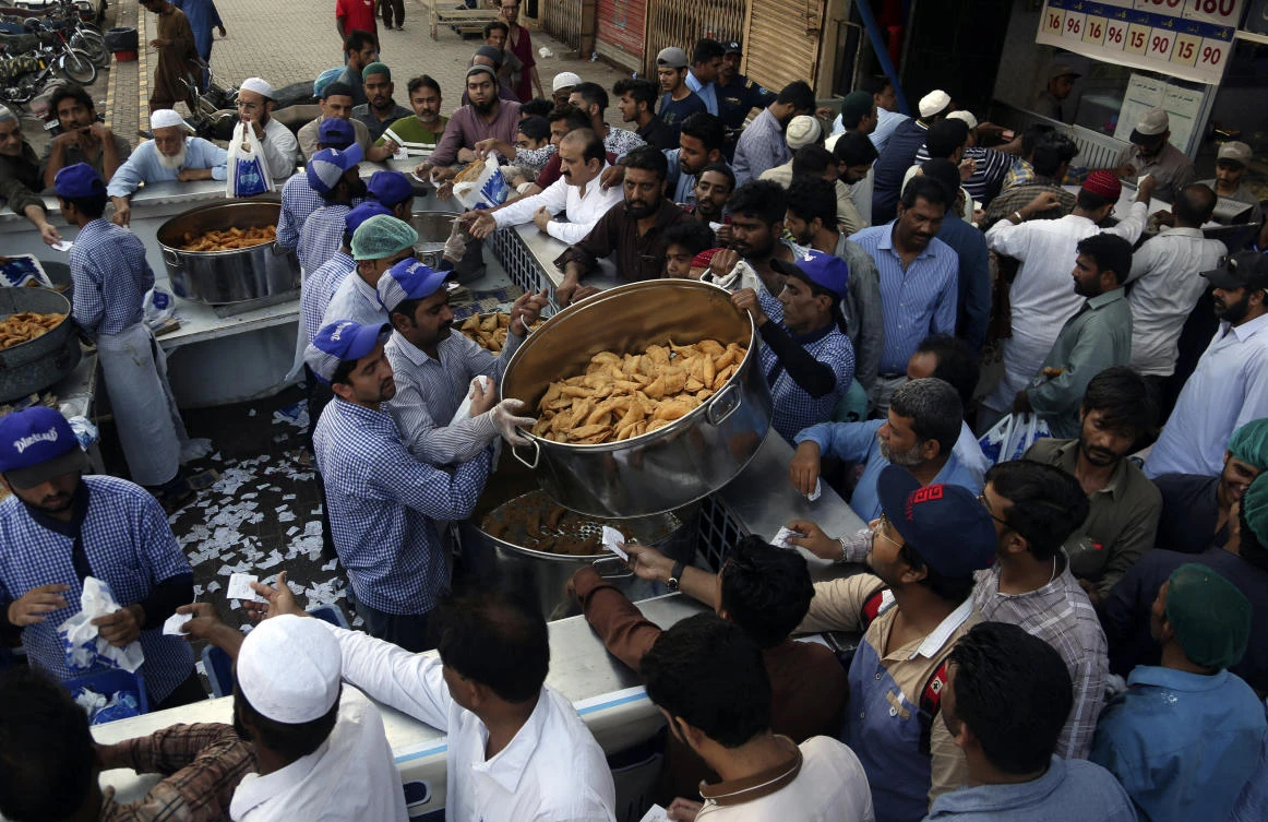 People buy food for the "Iftar" meal for Muslims to break their fast at sundown, during the fasting month of Ramadan at a mosque in Karachi Pakistan, Tuesday, May 7, 2019. Muslims around the world are observing Ramadan, the holiest month in Islamic calendar. (AP Photo/Muhammad Rizwan)
