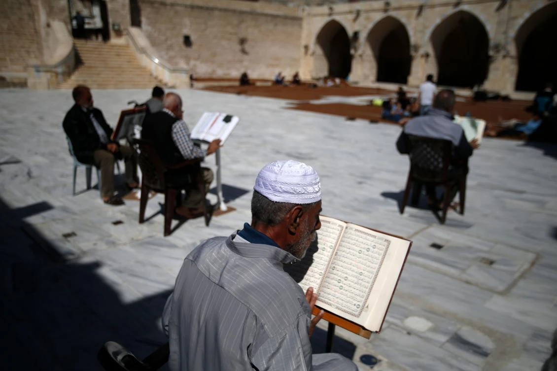 Palestinian men read the Koran outside the al-Omari mosque in Gaza City, on the second day of the Muslim holy fasting month of Ramadan on May 7, 2019. / AFP / MOHAMMED ABED