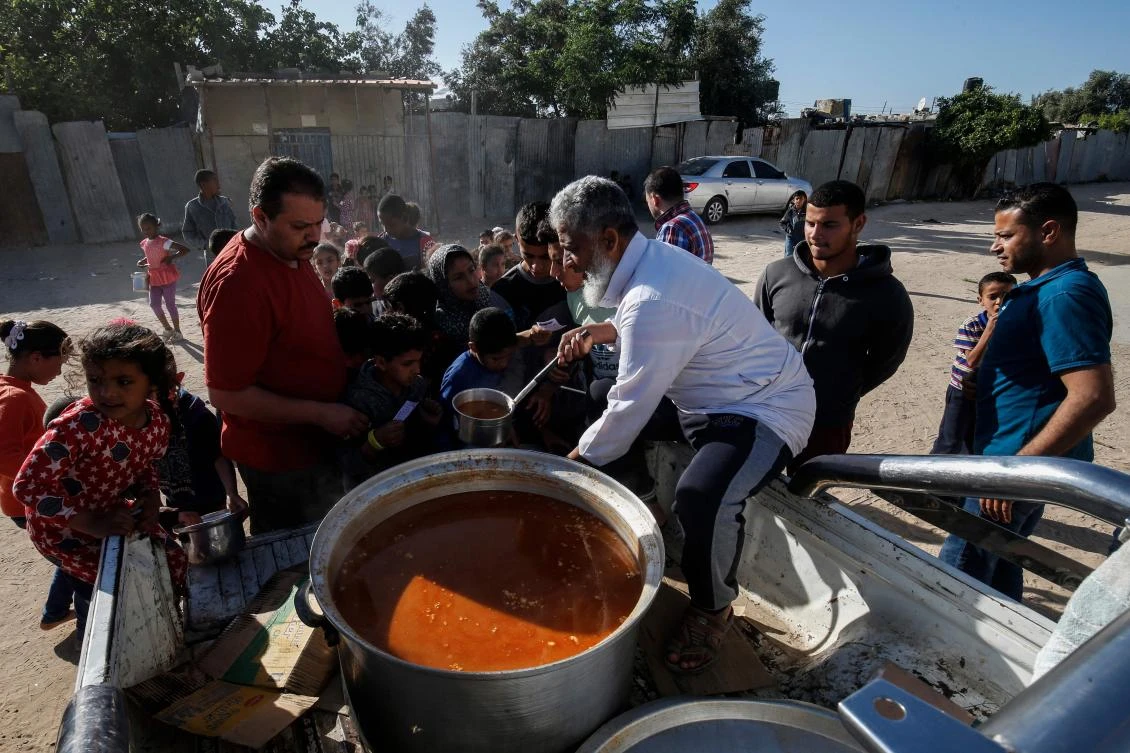 A Palestinian man passes out Iftar food for Muslim devotees prior to breaking their fast on the second day of the holy Muslim month of Ramadan in Rafah the southern Gaza Strip on May 7, 2019. / AFP / SAID KHATIB