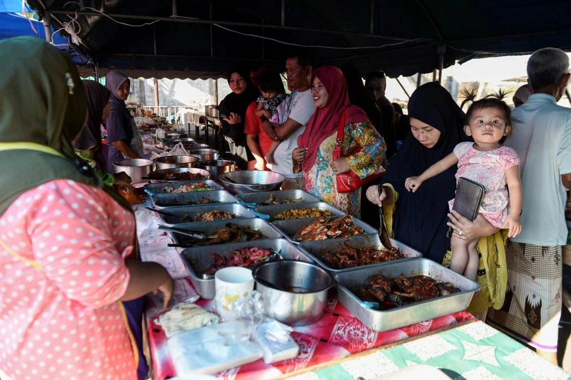 Thai Muslims buy food items at a market prior to breaking their fast during the holy month of Ramadan in Narathiwat on May 7, 2019. Muslims around the world abstain from eating, drinking and conducting sexual relations from sunrise to sunset during Ramadan, the holiest month in the Islamic calendar. / AFP / Madaree TOHLALA