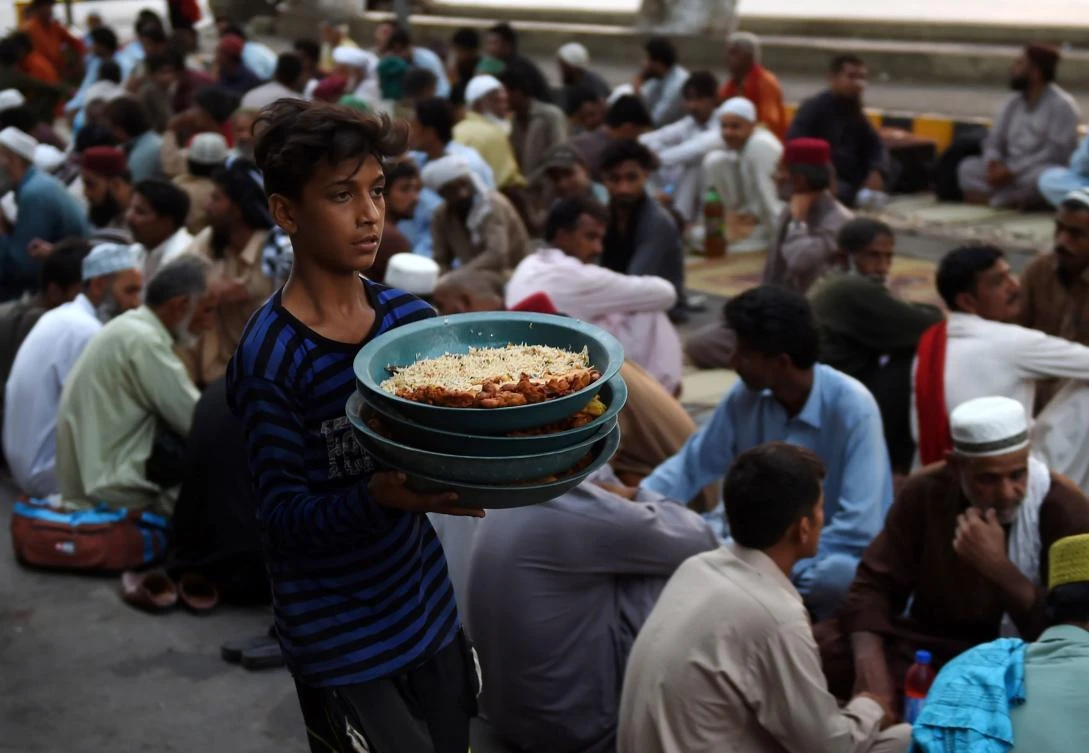 A Pakistani volunteer serves Iftar food to devotees prior to breaking their fast on the first day of the holy month of Ramadan along the roadside in Karachi on May 7, 2019. Muslims throughout the world are marking the month of Ramadan, the holiest month in the Islamic calendar during which Muslims fast from dawn until dusk. / AFP / RIZWAN TABASSUM