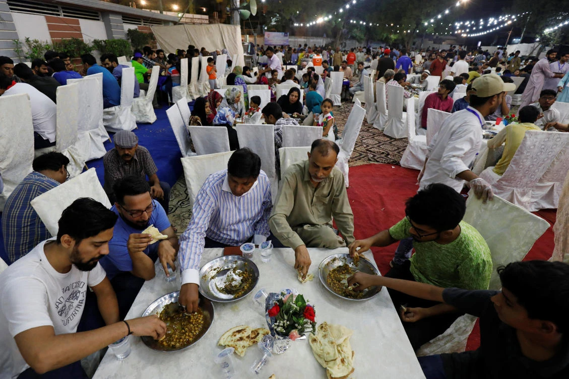 People eat charity food prepared with ostrich meat and chickpea, for the first day of the fasting month of Ramadan, in Karachi, Pakistan, May 7, 2019. REUTERS/Akhtar Soomro