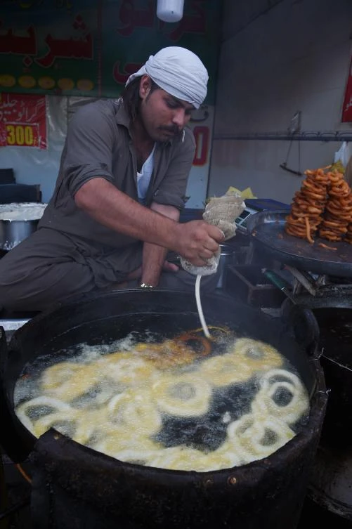 A Pakistani cook prepares Iftar food on a street before break their fast on the first day of the holy month of Ramadan in Rawalpindi on May 7, 2019. / AFP / FAROOQ NAEEM