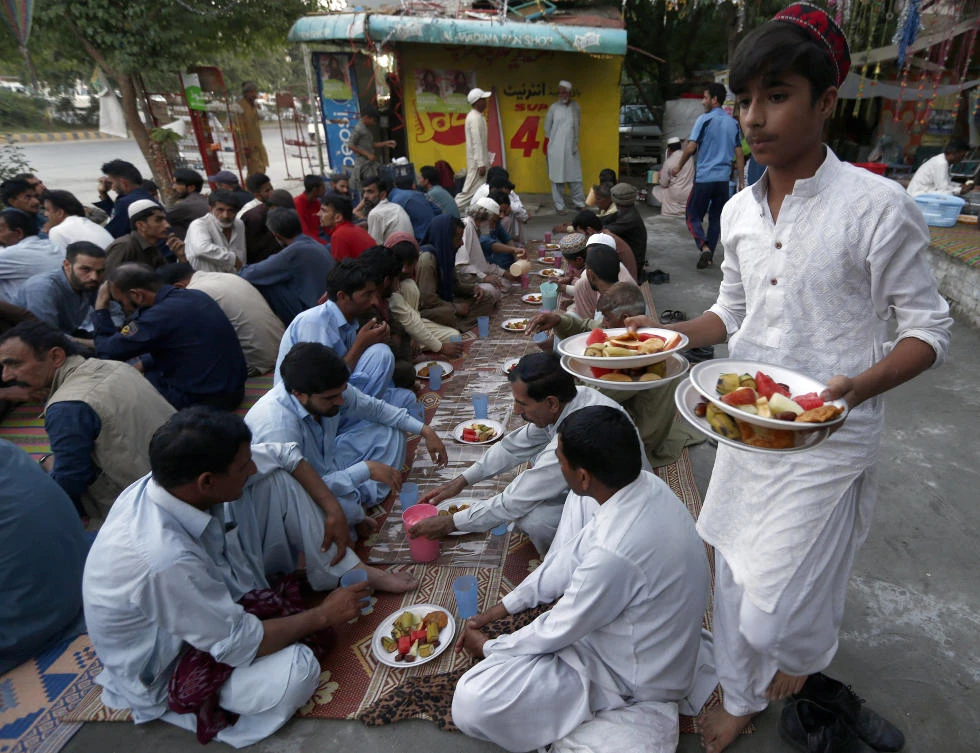 A volunteer distributes food for the "Iftar" meal for Muslims to break their fast at sundown, during the fasting month of Ramadan at a free food distribution point in Islamabad, Pakistan, Tuesday, May 7, 2019. Muslims around the world are observing Ramadan, the holiest month in Islamic calendar. (AP Photo/Anjum Naveed)