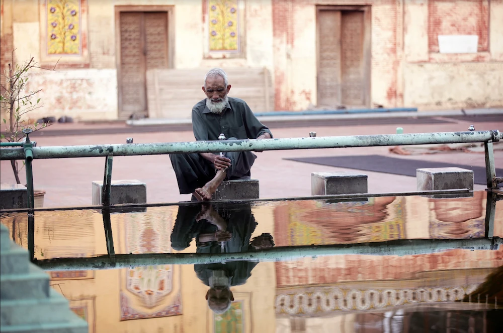 A reflection of a man is seen in a pool of water as washes his feet at a mosque during the fasting month of Ramadan in Lahore, Pakistan, May 16, 2019. (Reuters)