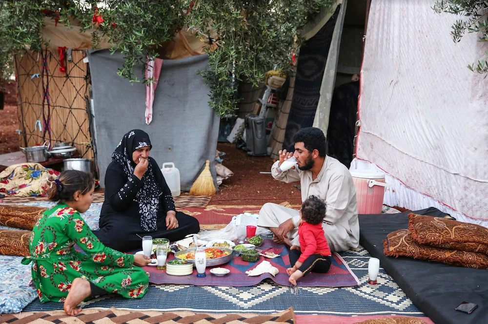 A displaced Syrian family break their fast in a field near a camp for displaced people in the village of Atme, in northern Idlib province on May 19, 2019. ( AFP)