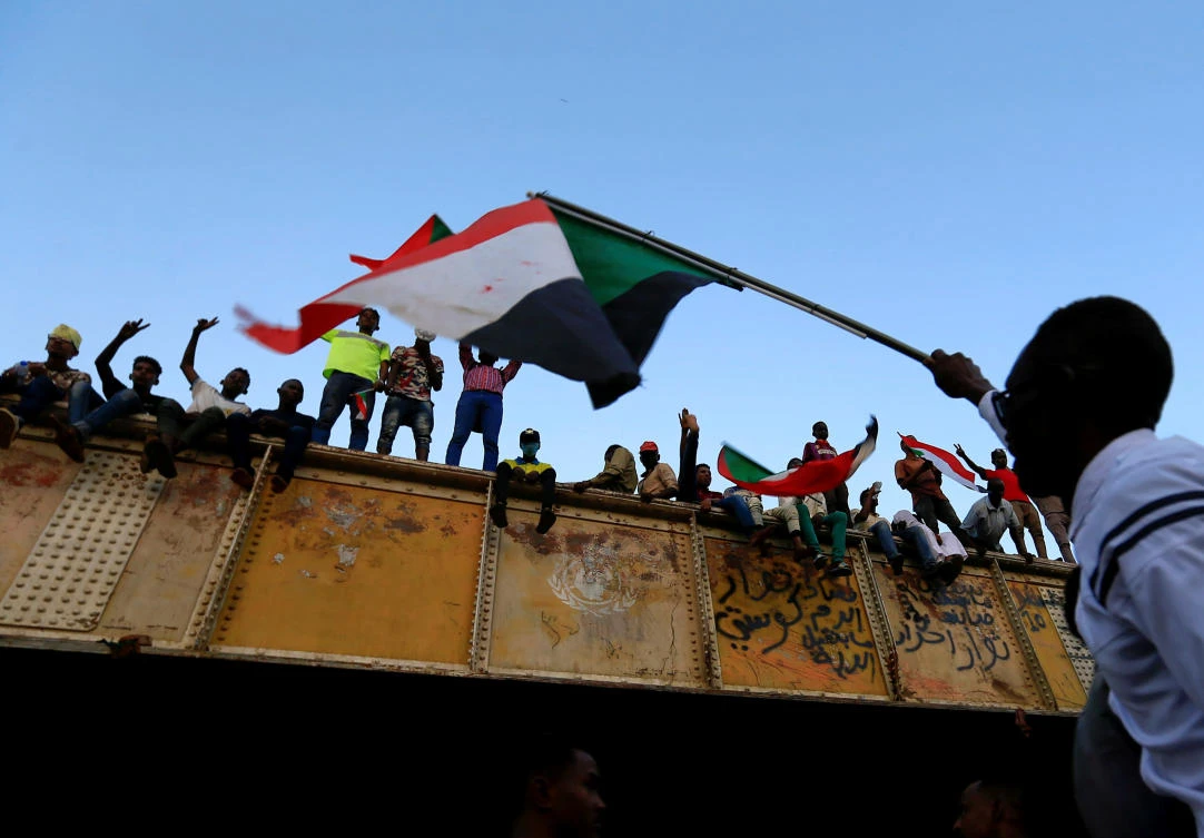 A Sudanese demonstrator from the Darfur region waves a Sudanese national flag from atop a bus as he arrives to be part of a mass anti-government protest outside Defense Ministry in Khartoum, Sudan April 30, 2019. (Reuters/Mohamed Nureldin Abdallah)