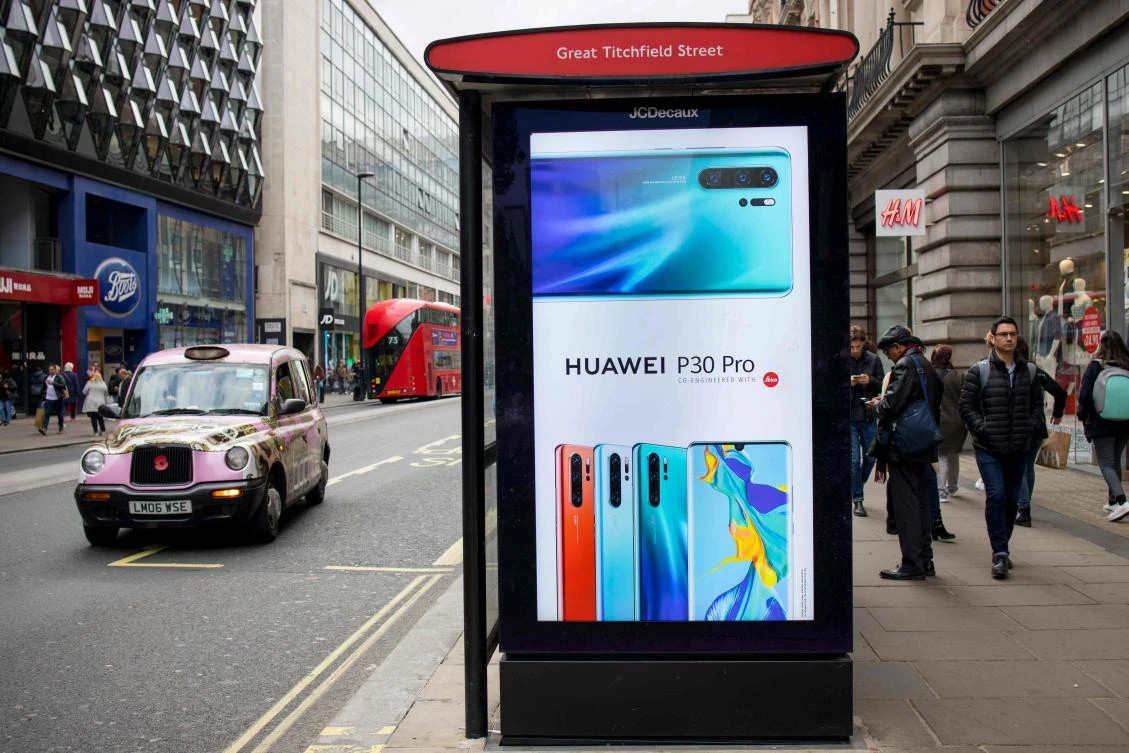 Pedestrians walk past a Huawei advert at a bus stop in central London. (AFP)