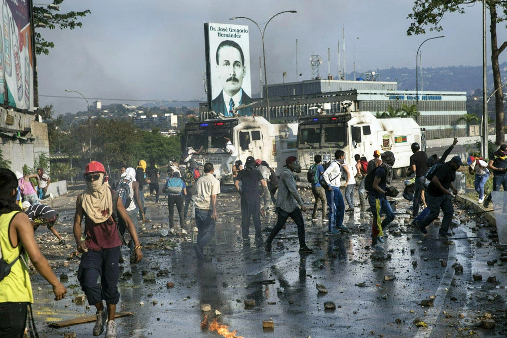 Anti-government protesters throw rocks at National Guard armored vehicles near La Carlota airbase during clashes between the two sides in Caracas, Venezuela, on May 1, 2019. (AP Photo/Rodrigo Abd)