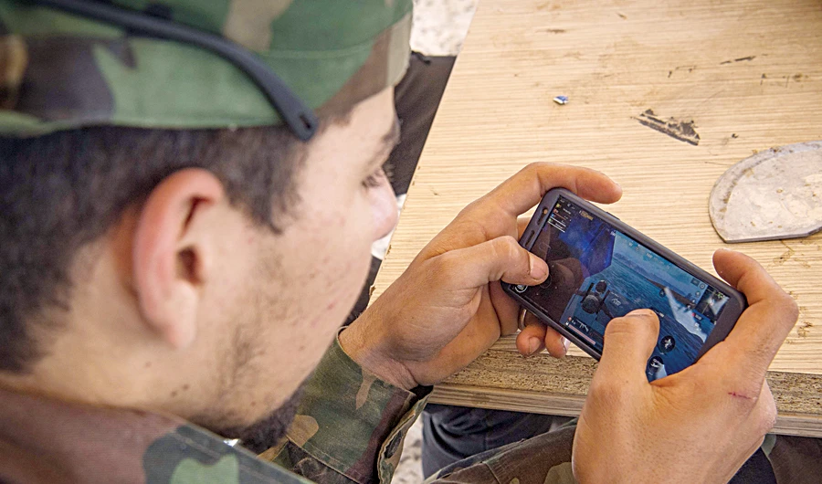 Troops loyal to the Tripoli government play online war video game on their phones on a military base in Tajoura, east of the Libyan capital, on Wednesday. (AFP)