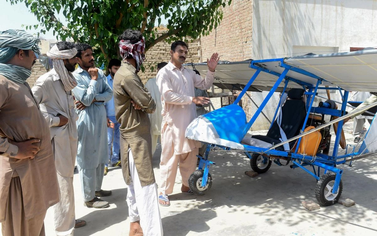 In this picture taken on April 8, 2019, Pakistani villager Muhammad Fayyaz (R) speaks to visitors as he stands alongside his small plane at his residence in Tabur village in central Punjab province. (AFP)