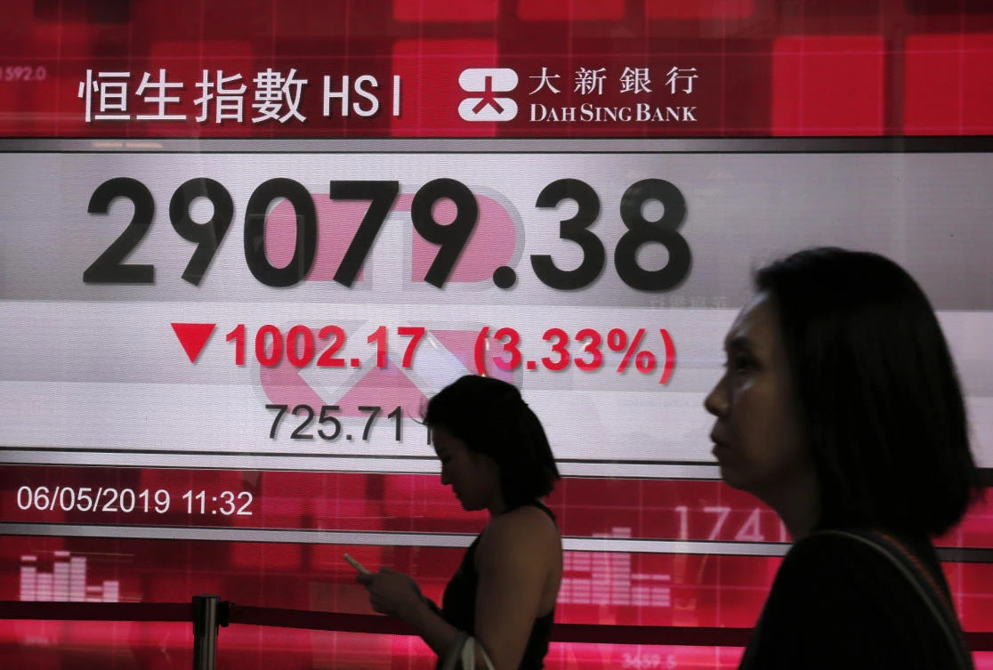 People walk past a bank’s electronic board showing the Hong Kong share index at the Hong Kong Stock Exchange yesterday. (AP Photo)
