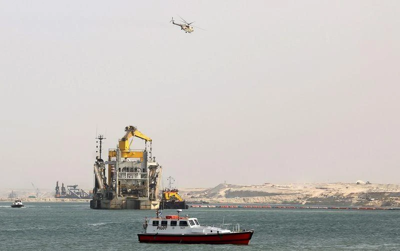 A helicopter flies overhead as tractors and dredgers work on Egypt’s New Suez Canal. (Reuters)