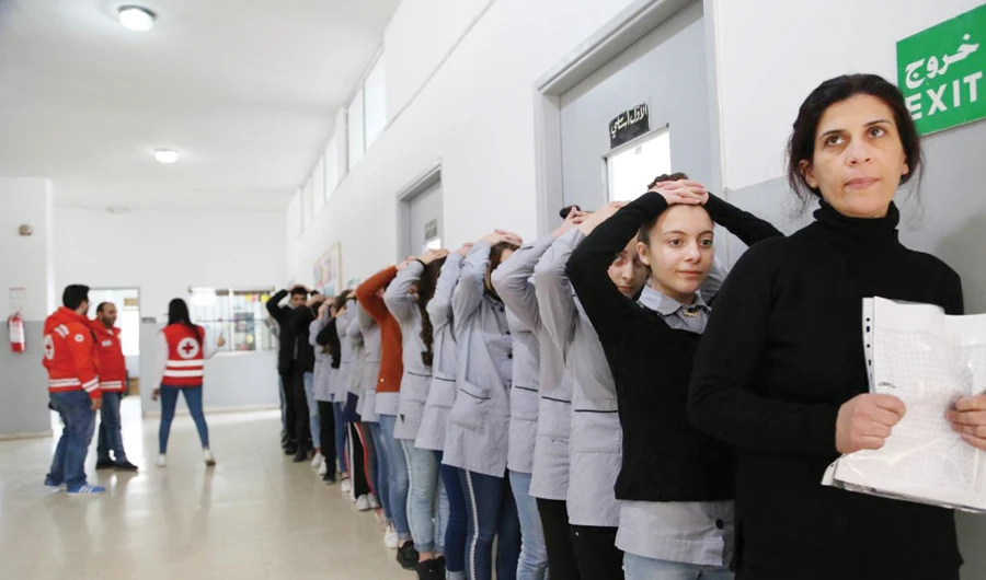 A teacher and students conduct a safety drill at Takmiliyat Al Kobba 2nd School in Tripoli, Lebanon, on March 27. (Thomson Reuters Foundation)