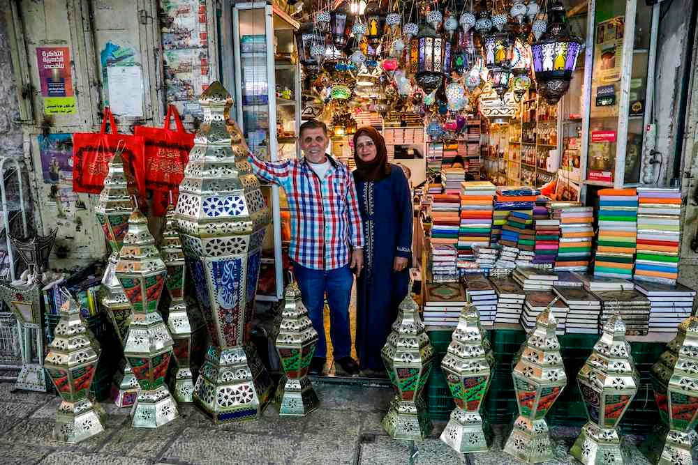Palestinian craftsman Issam Zughair stands with his wife next to an assortment of Ramadan lanterns in the entrance of his shop in the old city of Jerusalem. (AFP)
