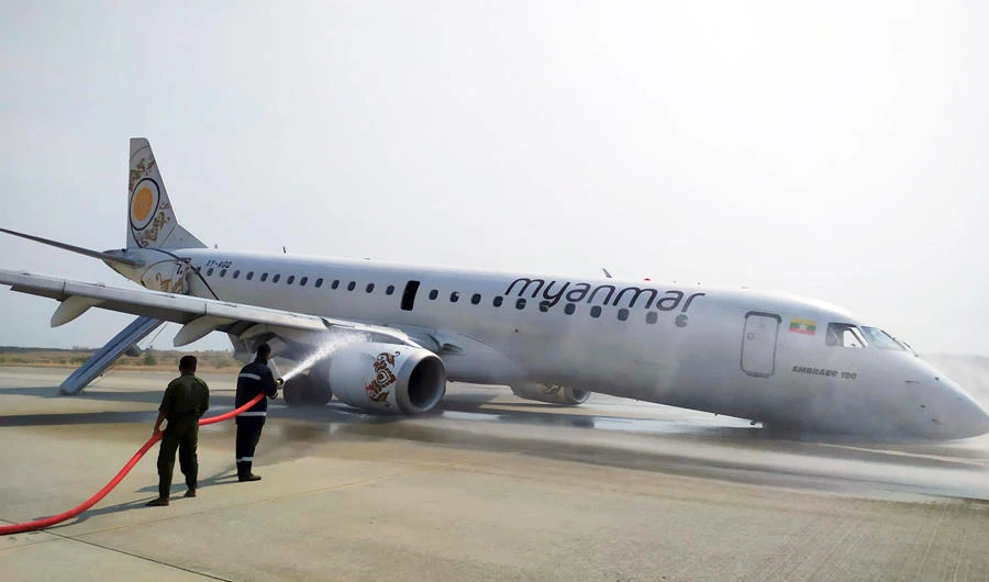 Firefighters work with hose on a plane of Myanmar National Airline (MNA) after an accident at Mandalay International airport Sunday, May 12, 2019, in Mandalay, Myanmar. (AP)