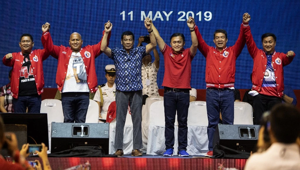 Philippine President Rodrigo Duterte, center, raises the hands of senatorial candidates during a campaign rally in Manila on May 11, 2019. (AFP)