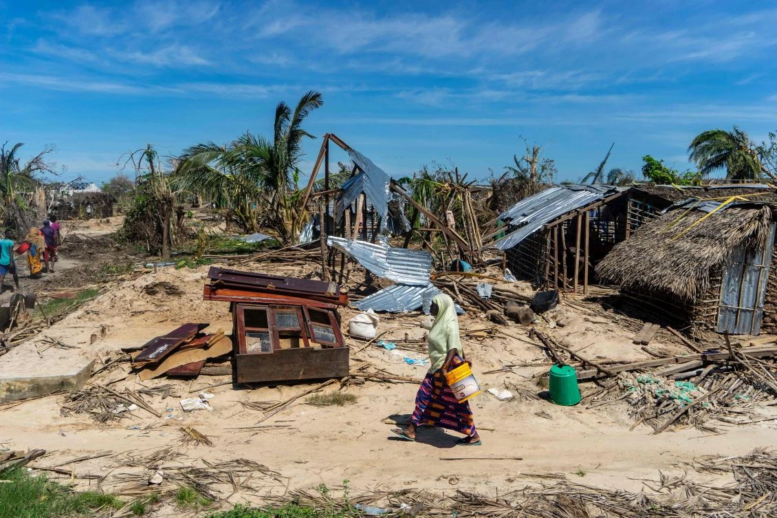 A woman walks past destroyed houses on May 13, 2019, on her way to an aid distribution centre in the coastal village of Guludo on Ibo Island, in Mozambique's Cabo Delgado province, in the aftermath of a devastating cyclone. (AFP)
