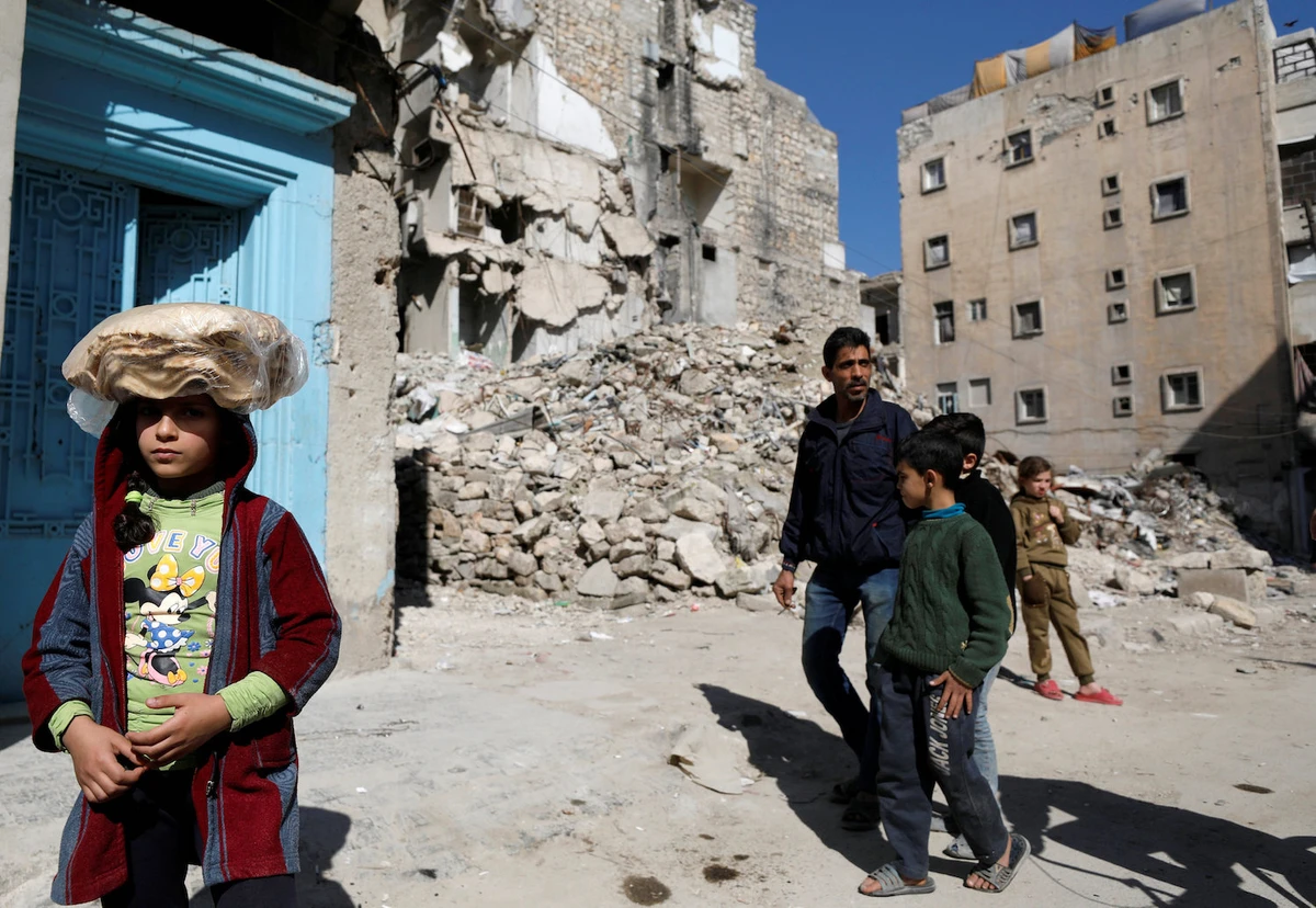 A girl carries a stack of bread on her head as she walks near rubble of damaged buildings in Aleppo, Syria. (File/Reuters)