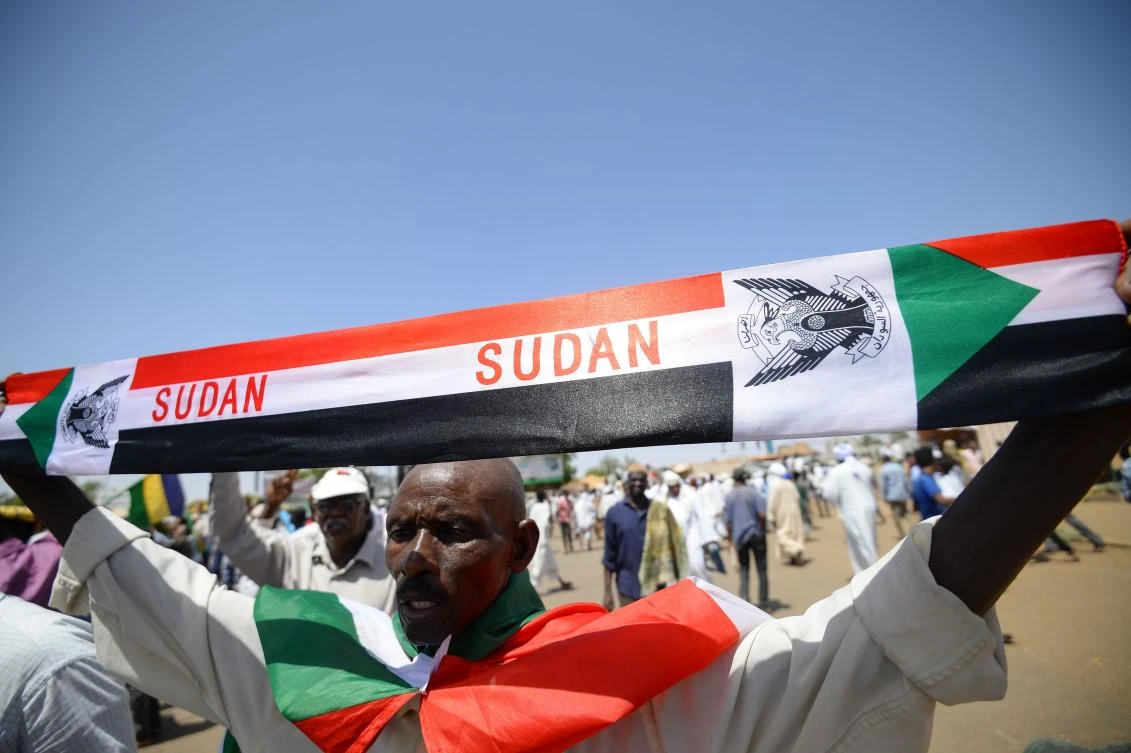 A Sudanese protester spreads a banner with the colours of the national flag near the military headquarters in the capital Khartoum on May 17, 2019, during an ongoing sit-in demanding a civilian-led government transition. (AFP)