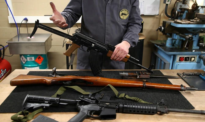 Michel Baud, gunsmith at the Swiss Gun Center in Geneva, holds a Kalashnikov rifle next to a Musket 31 and an M-16 ahead of a May 19 referendum on proposals to tighten Switzerland's weapon ownership laws in line with EU steps. (REUTERS/Denis Balibouse)