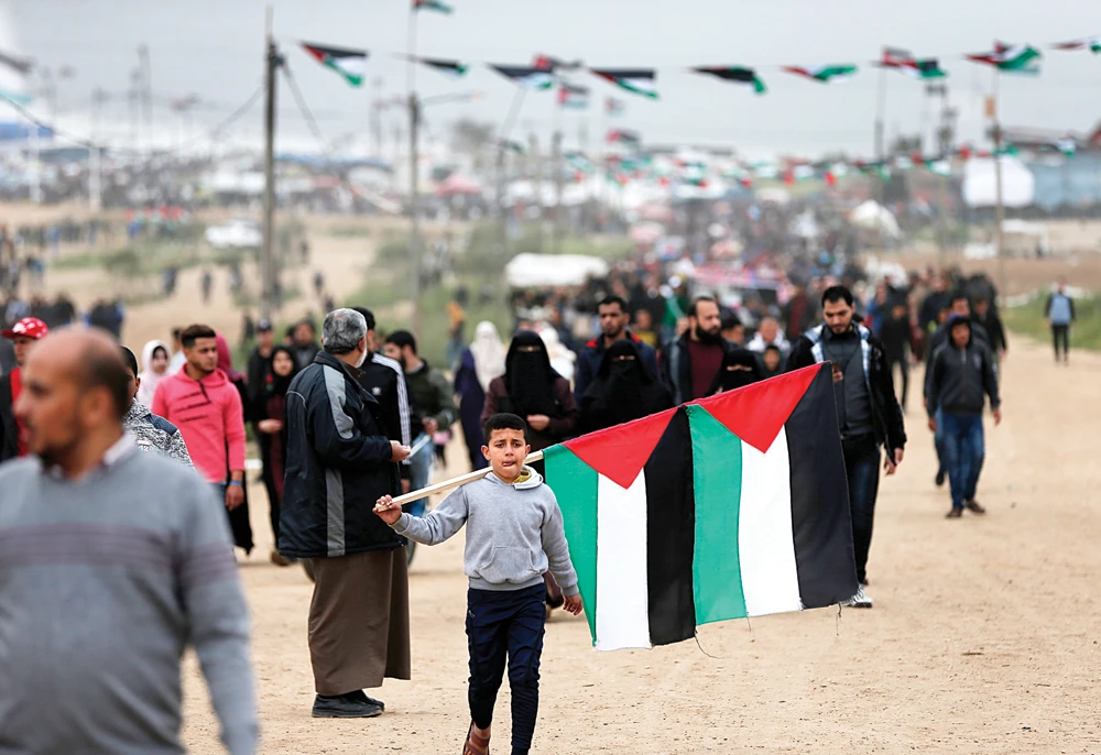 A Palestinian boy carries national flags at a demonstration near the border with Israel in Malaka, east of Gaza City. (AFP/File photo)