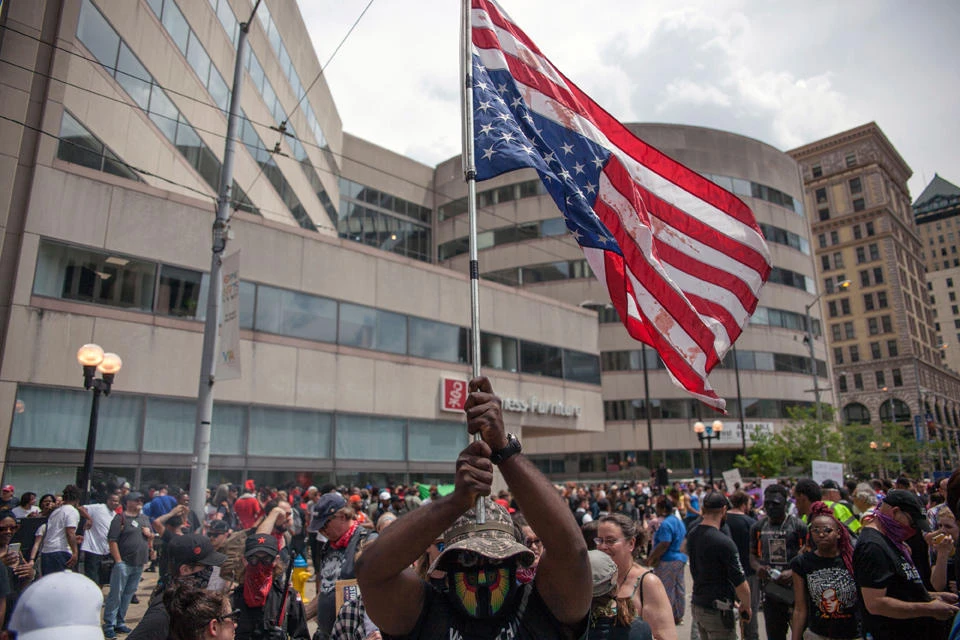 A counter-protester holds a upside down American flag during a demonstration against a small group from the KKK-affiliated Honorable Sacred Knights who gathered for a rally in Dayton, Ohio, on May 25, 2019. (AFP / Seth Herald)