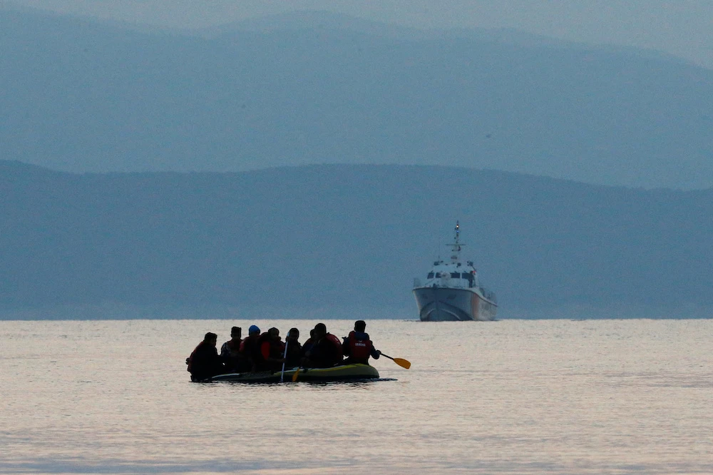 Migrants in a dinghy paddle their way on the Mediterranean Sea to attempt crossing to the Greek island of Kos, as a Turkish Coast Guard ship patrols off the shores off Bodrum, Turkey. (File/Reuters)