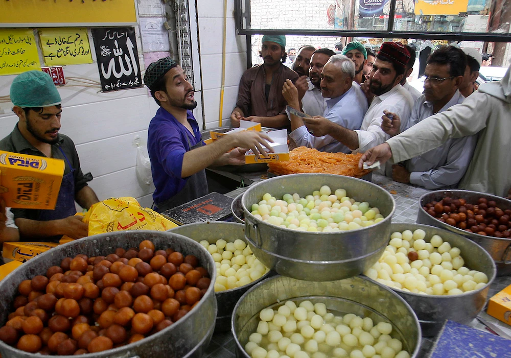 People buy sweets at a shop in preparation for the upcoming Eid Al-Fitr celebrations, in Peshawar, Pakistan. (AP)