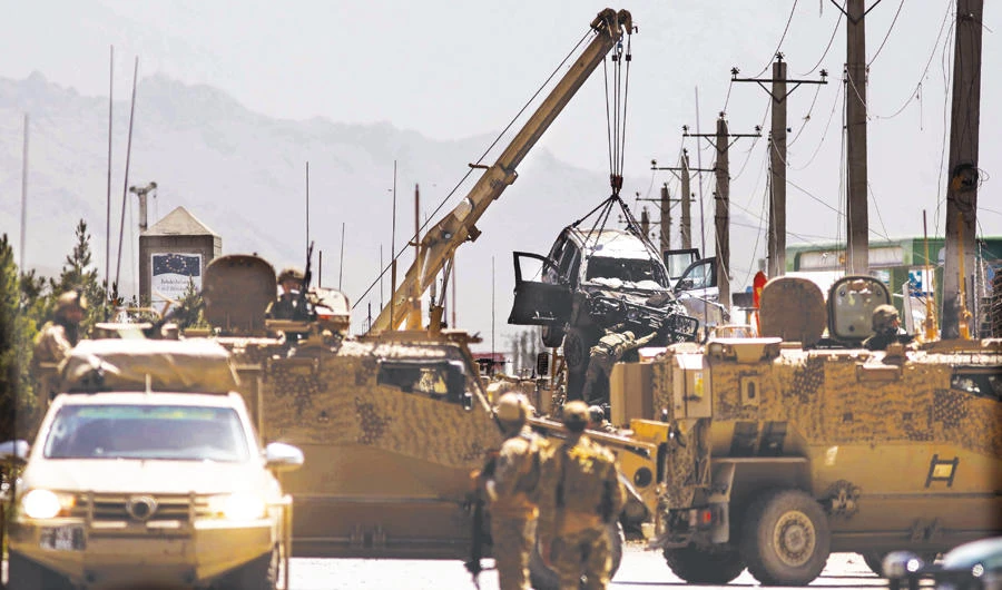 International forces belonging to NATO’s Resolute Support mission remove a damaged vehicle with a crane at the site of a car bomb attack in Kabul on Friday. (AFP)