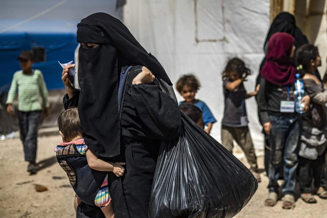 A woman carries a child and her belongings at Al-Hol camp for displaced people in Al-Hasakeh governorate in northeastern Syria, on June 3, 2019. (AFP)