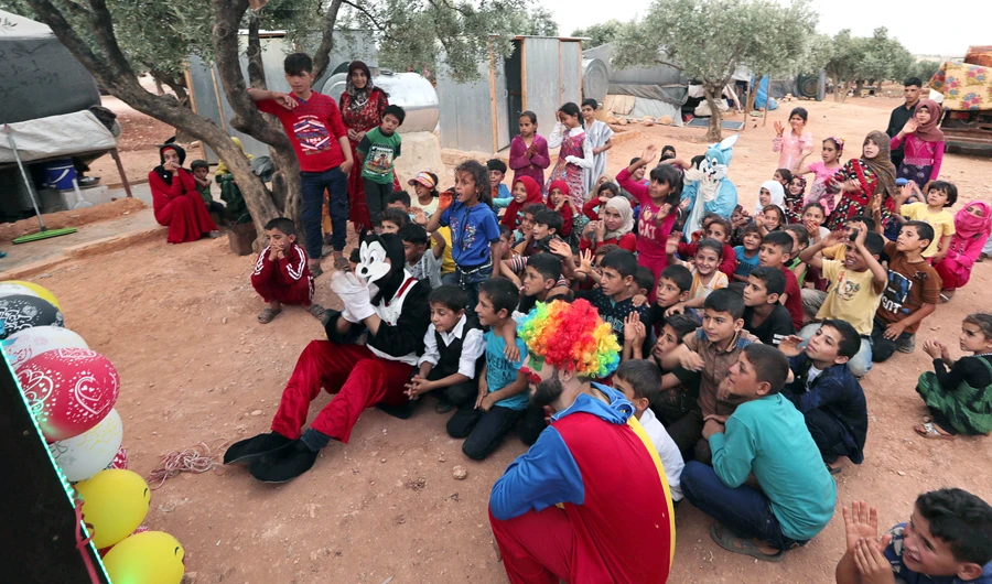 A man dressed as clown entertains displaced Syrian refugee children during the first day of the Muslim holiday of Eid Al-Fitr, in an olive grove at the north of Idlib Countryside, Syria June 4, 2019. (Reuters)