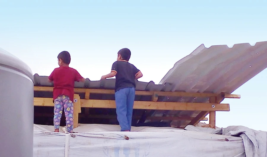 Two boys watch the demolition of their refugee camp as Lebanon fears building work inside tents could represent the start of resettlement or permanent residence of Syrian refugees. (Photo/Supplied)