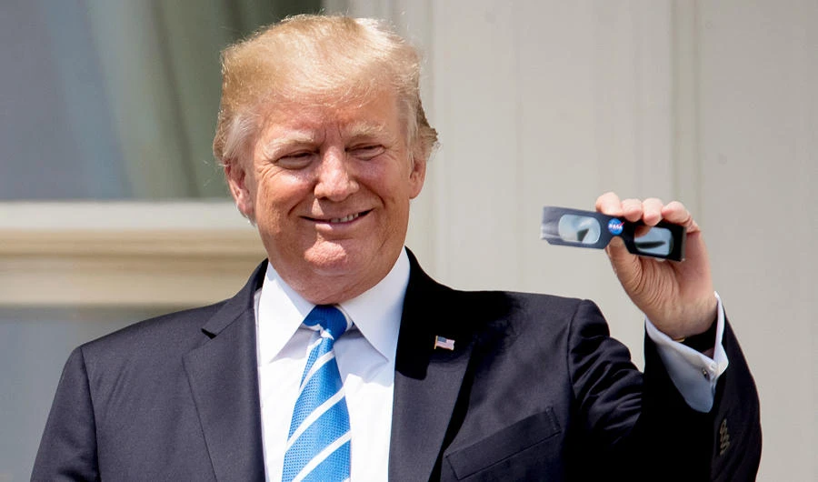 President Donald Trump holds up protective glasses as he arrives to view the solar eclipse at the White House in Washington, in this photo taken on Aug. 21, 2017. (AP)