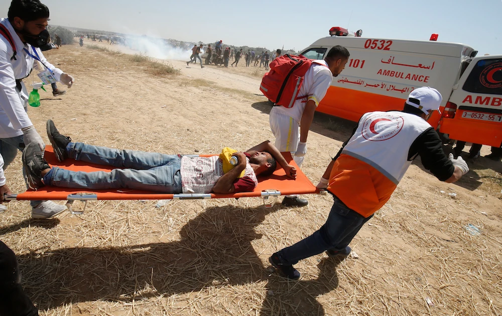 Palestinian medics carry a wounded demonstrator east of Khan Yunis in the southern Gaza Strip, during a protest. (AFP)