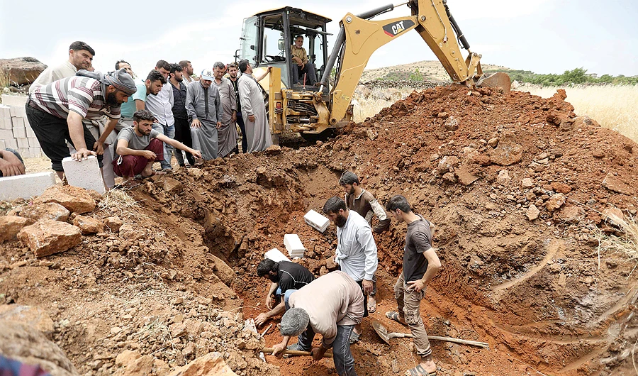 Syrians prepare a common tomb for the victims of an aerial bombardment in the country's northern Idlib province on June 5 in the village of Kafr Uweid. (AFP)
