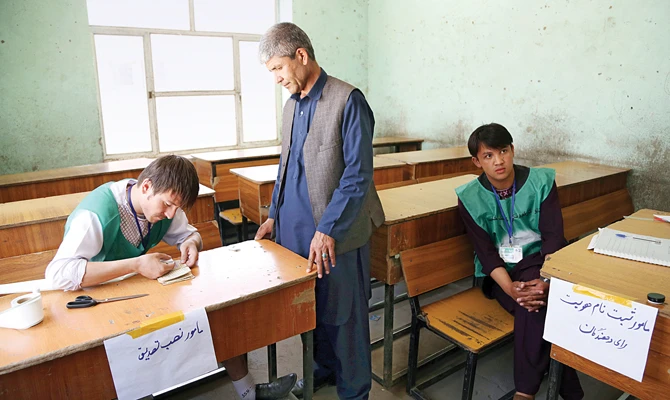 An employee registers a resident at a voter registration center for the upcoming presidential election in Kabul. (AP)