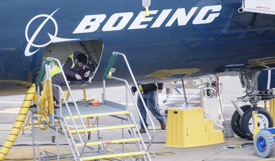 Employees work in the cargo hold of a Boeing 727 MAX 9 test plane outside the company's factory, on March 14, 2019 in Renton, Washington. (AFP)