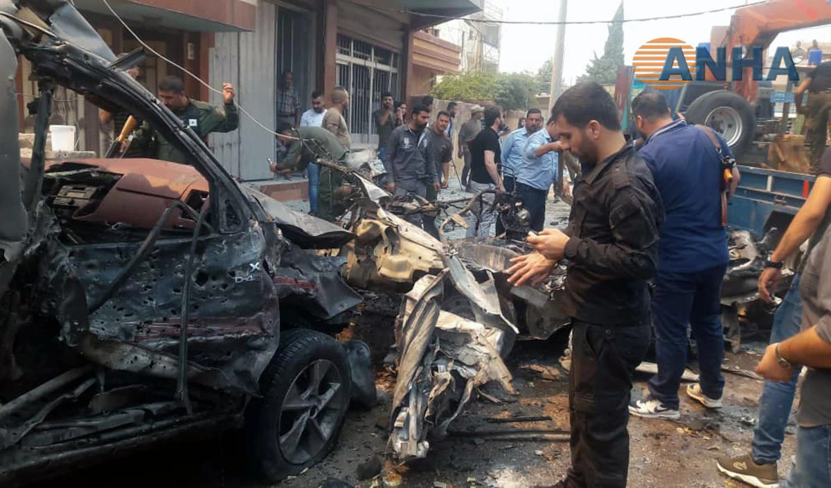 This image provided by Hawar News Agency, ANHA, an online Kurdish news service, shows people inspecting debris at the scene of a car bombing in the town of Qamishli, eastern Syria on Monday, June 17, 2019. (ANHA via AP)