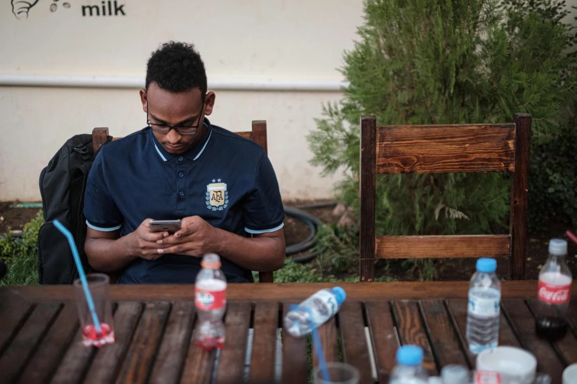 A Sudanese man uses his smart-phone to access the Internet at a cafe in which an hour of Internet costs 50 Sudanese pounds, which is approximately one US dollar, on June 17, 2019 in an upscale Khartoum district. (AFP/Yasuyoshi Chiba)