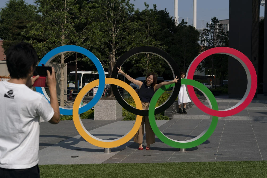 Tokyo residents Yuuma Sakai, foreground, takes photos of his wife, Hiroyo, with the Olympic rings set up near New National Stadium in Tokyo. (AP/Jae C. Hong)