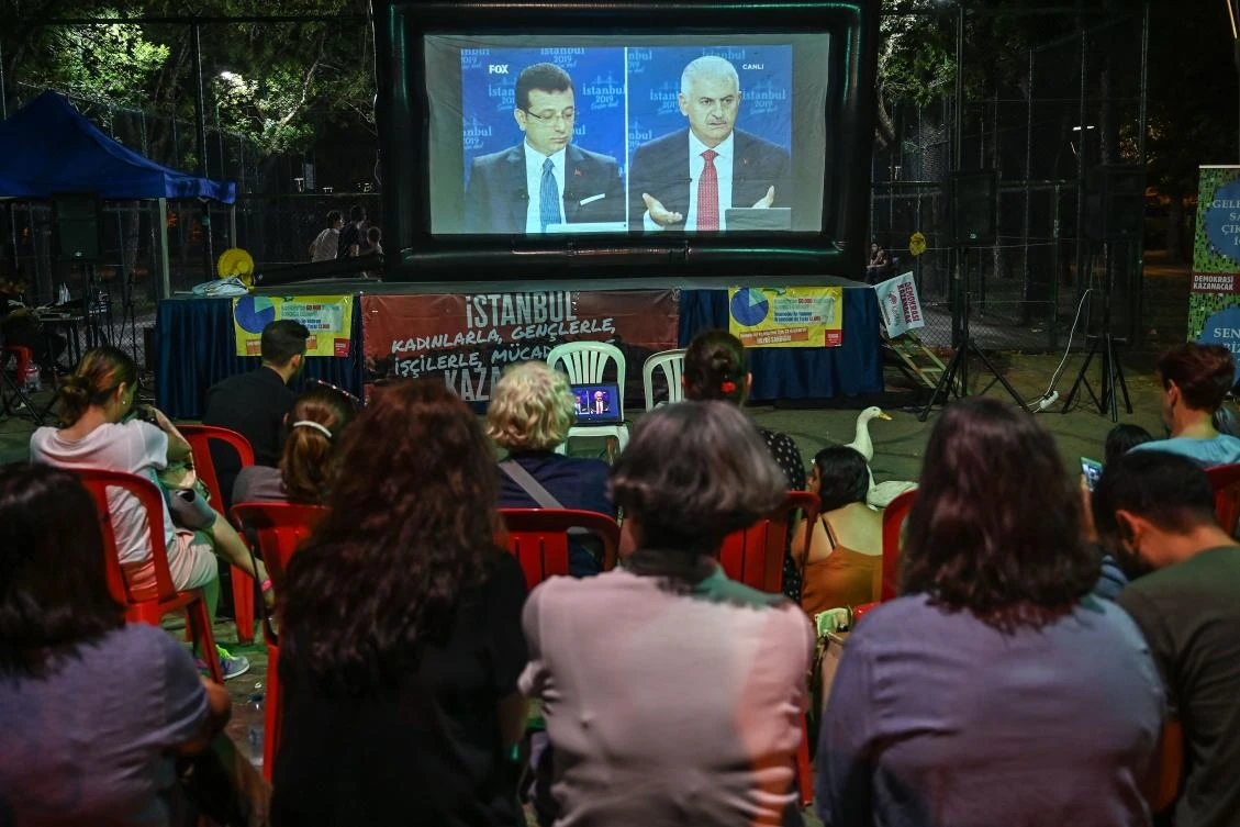 Residents watch a live broadcast of a televised debate between Istanbul’s mayoral candidate Binali Yildirim, right, of Turkey’s ruling Justice and Development Party, and Istanbul’s deposed mayor Ekrem Imamoglu of the Republican Peoples Party ahead of June 23 re-run of Istanbul elections. (AFP)
