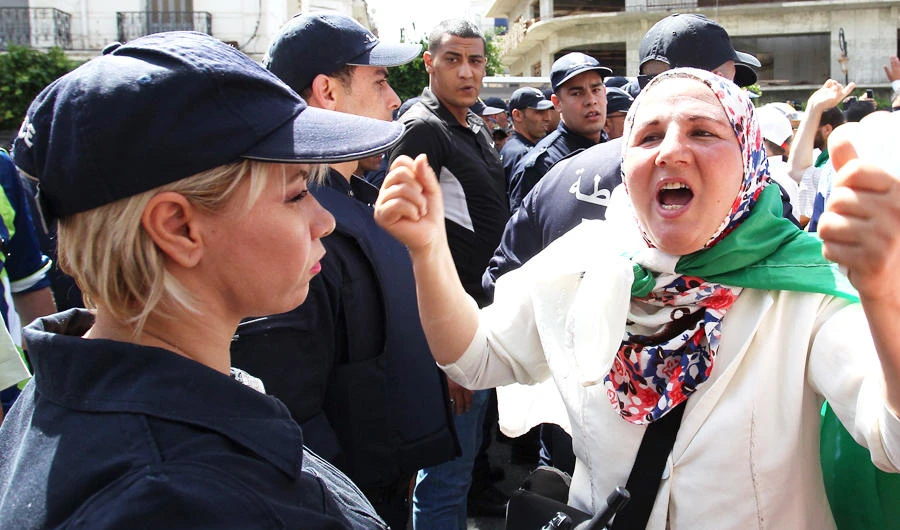 An Algerian protester shouts slogans as riot police stand guard during the weekly Friday demonstration in Algiers. (AFP)