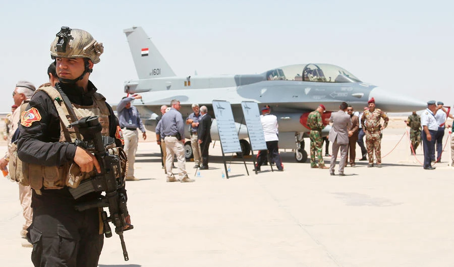 A member of the Iraqi SWAT team stands guard as security forces and others gather next to a US-made F-16 fighter jet at Balad Air Base, Iraq. (AP)